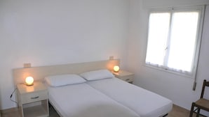 En dubbelsäng med två sängbord, ett litet bord och en stol.