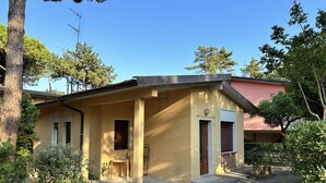 A two-story building with a yellow facade, a covered porch, and a brick entrance. - Holiday B A in Bibione (San Michele al Tagliamento)