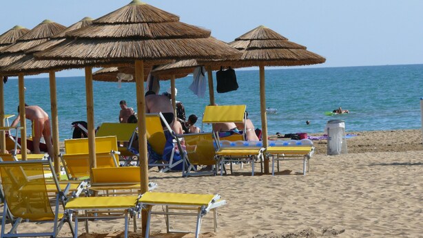 A beach with yellow lounge chairs and thatched umbrellas. - Master B 1P in Bibione (San Michele al Tagliamento)