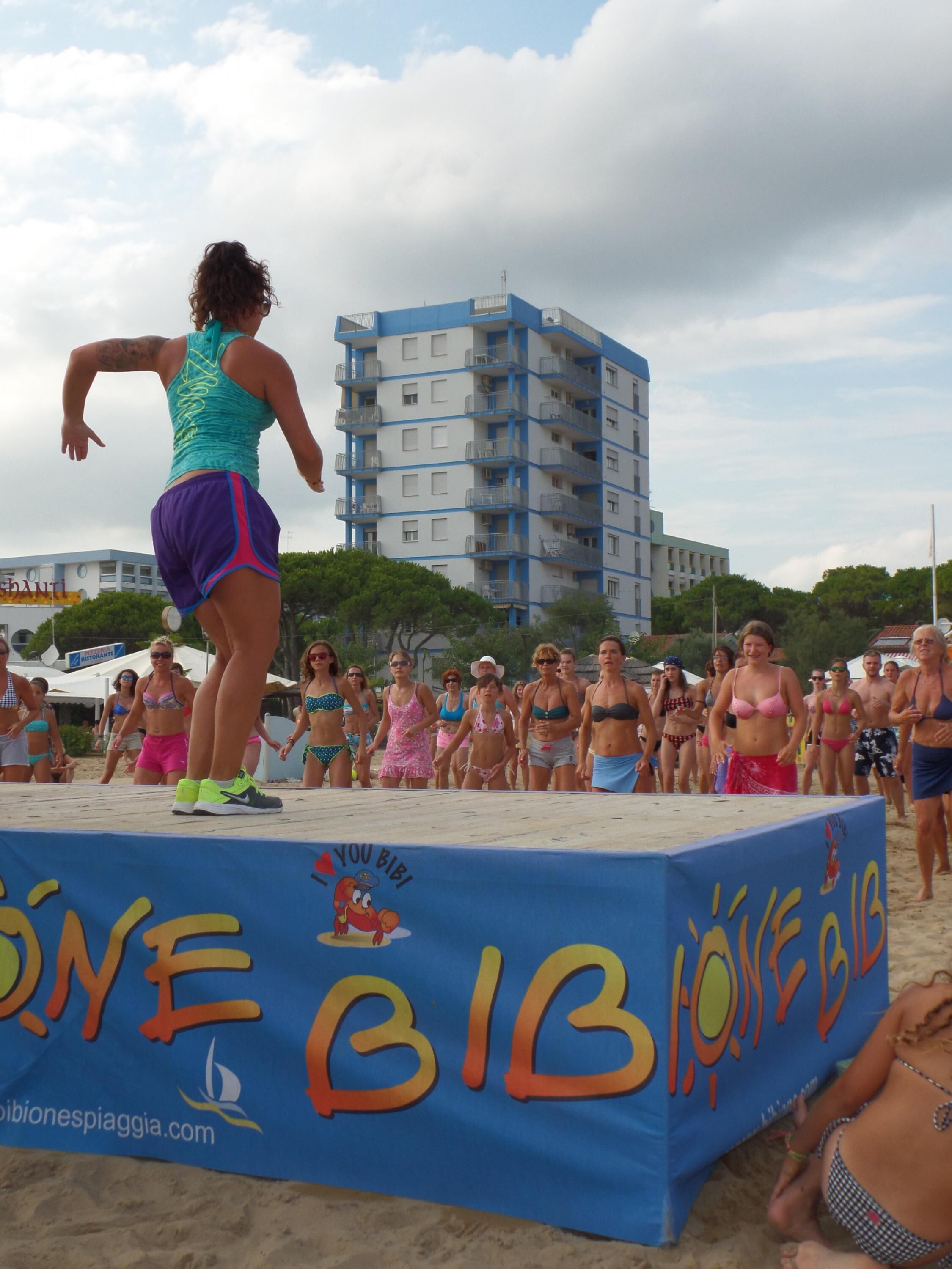 A beach event with a stage and a crowd.
