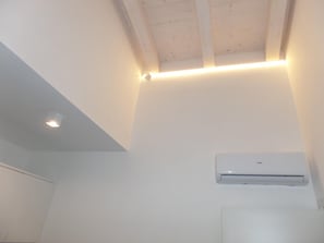 A room with a sloped ceiling, recessed lighting, and an air conditioning unit mounted on the wall. - Villa Onda D in Bibione (San Michele al Tagliamento)