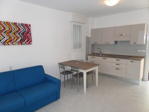 Une cuisine moderne avec un coin repas, un canapé bleu et une œuvre d’art colorée accrochée au mur.