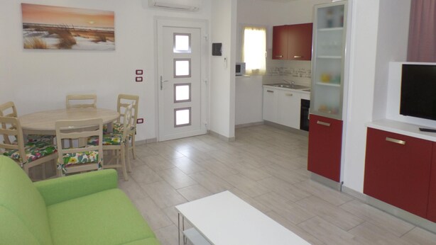 A compact living space with a dining area, a kitchenette, and a TV. - Villa Angi in Bibione (San Michele al Tagliamento)