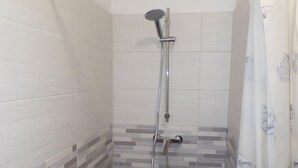 A shower area with a tiled wall, a showerhead, and a curtain. - Villa Angi in Bibione (San Michele al Tagliamento)