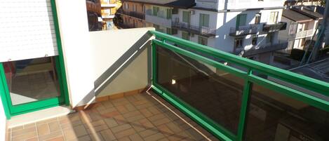 A balcony with a tiled floor and a green railing.