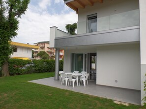 Ein modernes Haus mit einer Terrassenanlage, inklusive Tisch und Stühlen.
