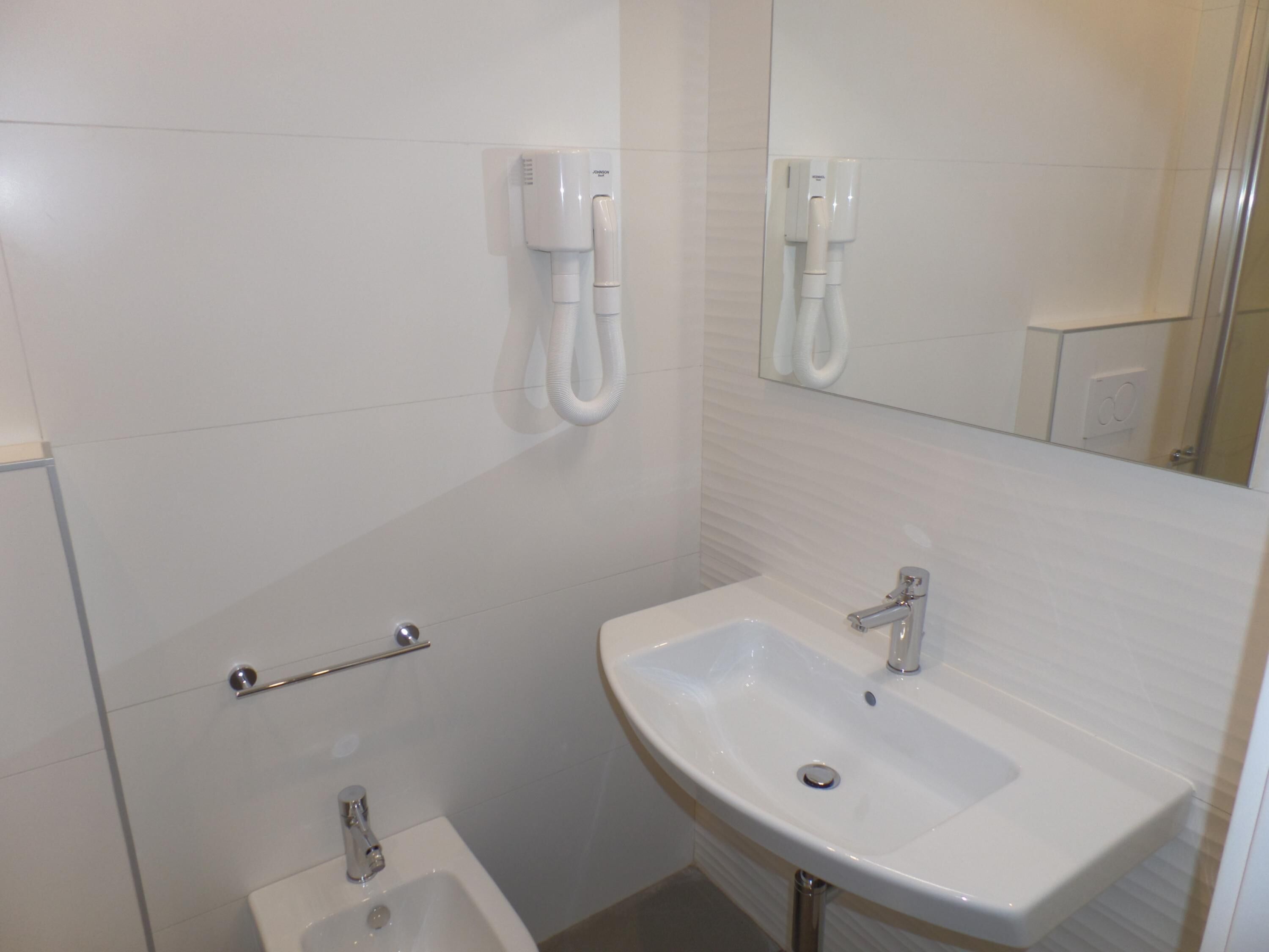 Une salle de bain avec un lavabo blanc, un miroir et des toilettes.