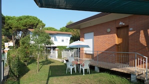 A patio with a table and chairs, a small garden, and a brick house with a door and window. - Holiday 5 in Bibione (San Michele al Tagliamento)