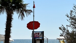 A beach with a lifeguard tower, a lifeguard chair, and a lifeguard flag. - Melograno A C2 in Bibione (San Michele al Tagliamento)