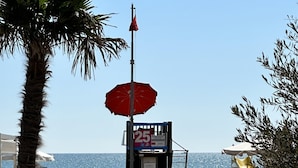 Ein Strand mit einem Rettungsturm, einem Rettungssitz und einer Rettungsflagge.