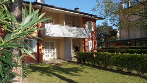 A two-story house with a balcony, a front door, and a small garden area.