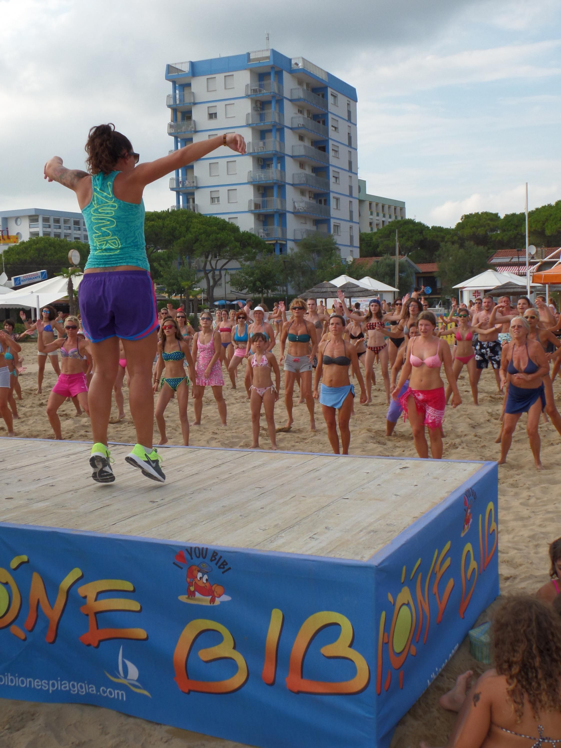 A beach event with a stage and a crowd.