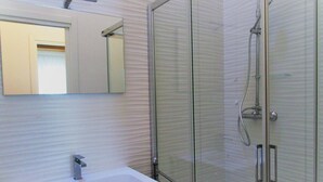A bathroom with a glass shower enclosure, a sink, and a mirror. - Polaris B in Bibione (San Michele al Tagliamento)