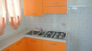 Eine Küche mit orangenen Schränken, einem Gasherd und einer Spüle mit zwei Becken.
