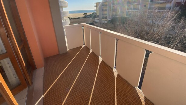 Een balkon met uitzicht op een strand en gebouwen.