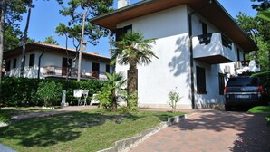 A two-story house with a white exterior, a tiled roof, and a paved driveway. - Pinea 35 in Bibione With 2 Bedrooms and 1 Bathrooms (San Michele al Tagliamento)