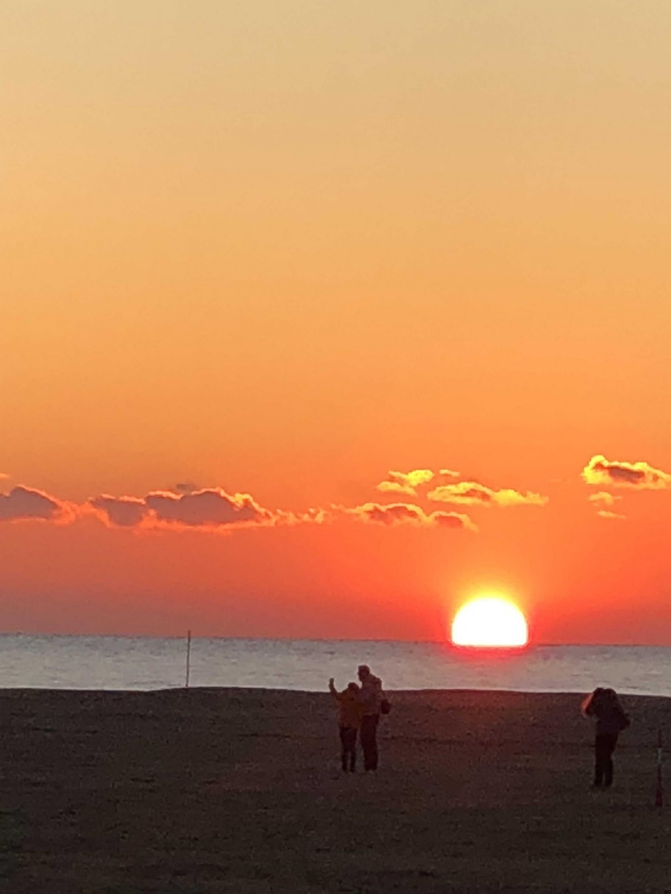 Ein Sonnenuntergang über einem Strand mit Personen im Schatten
