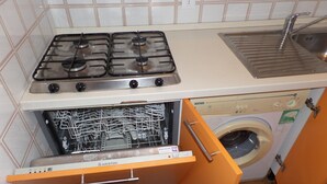 Kompakti keittiö, jossa on kaasuliesi, sis äänrakennettu pesukone ja astianpesukone.