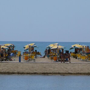 A beach with rows of sun loungers and umbrellas.