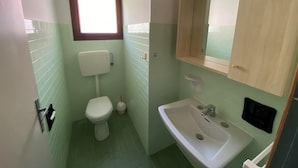A small bathroom with a toilet, sink, and window. - Rose in Bibione With 3 Bedrooms and 1 Bathrooms (San Michele al Tagliamento)