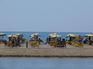 A beach with rows of sun umbrellas and beach chairs. - Villa Beba 1P in Bibione (San Michele al Tagliamento)