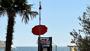 A beach with a lifeguard tower, a lifeguard chair, and a lifeguard flag. - Villa Beba 1P in Bibione (San Michele al Tagliamento)