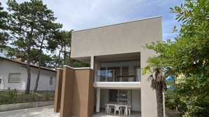 A modern two-story building with a flat roof, a balcony, and a paved entrance area. - Diana 5 in Bibione With 1 Bedrooms and 1 Bathrooms (San Michele al Tagliamento)