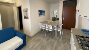 Une cuisine compacte avec une table et des chaises, un canapé bleu et une cuisinière.