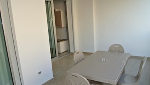Een eethoek met een tafel en stoelen, een schuifdeur naar een opslagruimte en een stopcontact op de muur.