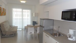 Een moderne keuken met een ingebouwde magnetron, een roestvrijstalen koelkast en een spoelbak. Er is een eethoek met een tafel en stoelen.
