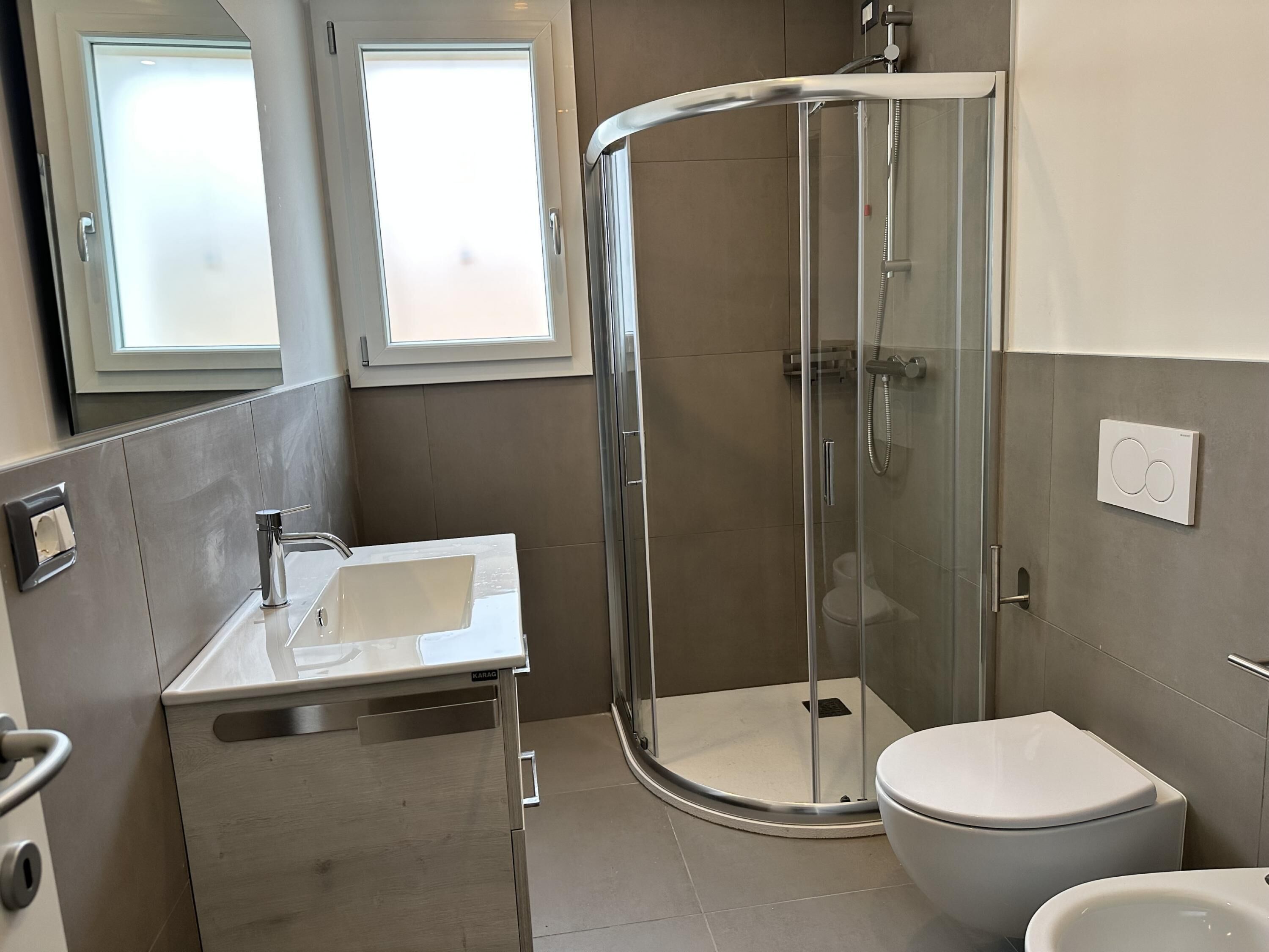A modern bathroom with a glass-enclosed shower, a sink, and a toilet.