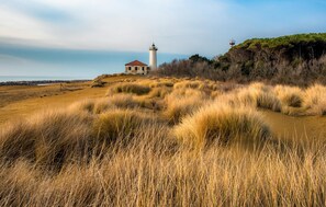 A lighthouse on a grassy hill with a clear sky.