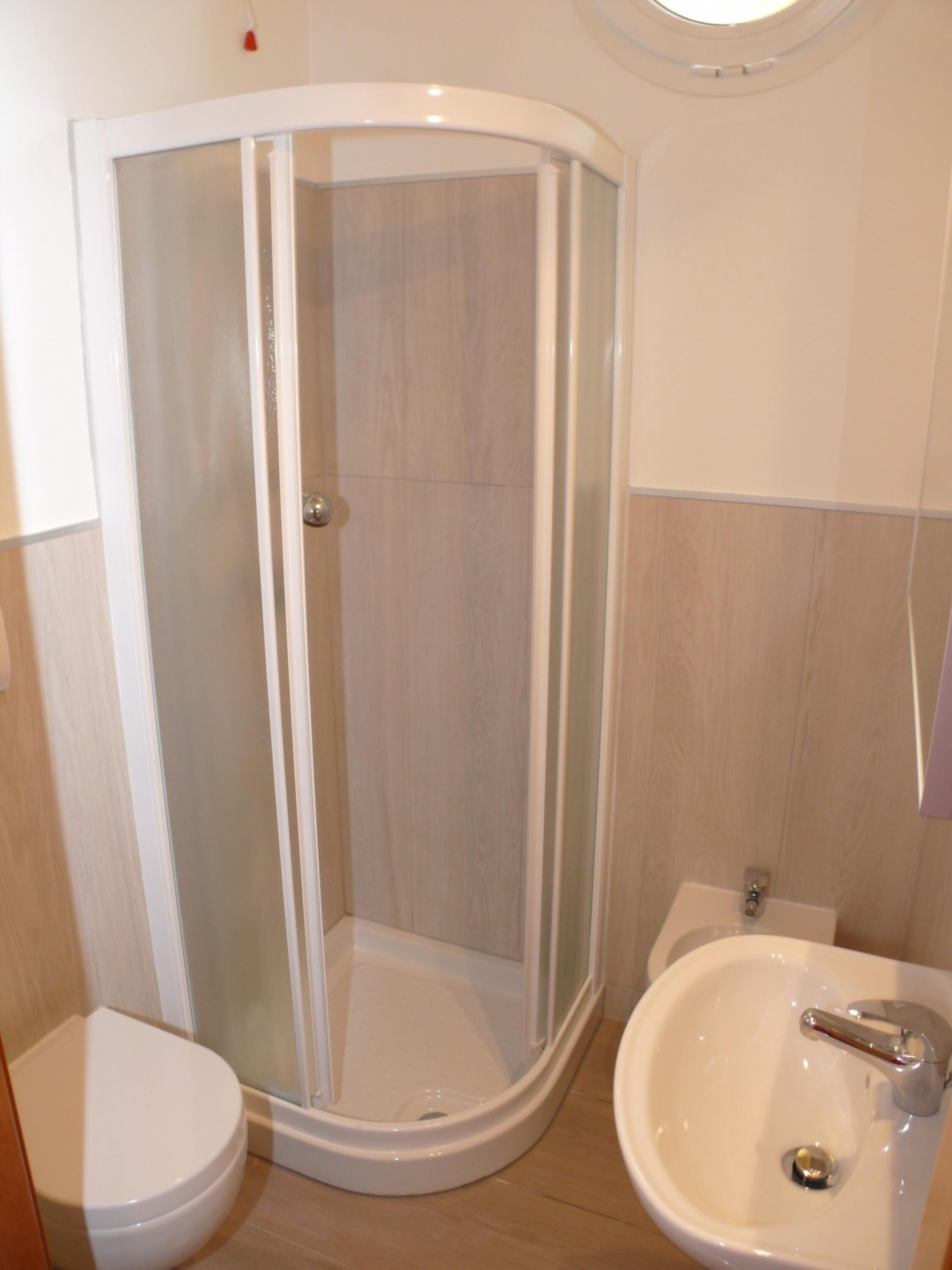 Un baño con ducha de vidrio, inodoro y lavabo.
