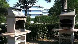 Zwei Steinkohleöfen im Freien in einem Garten mit einem gepflasterten Weg und einem Gebäude im Hintergrund.