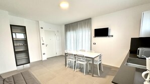 A modern kitchen with a dining area, white appliances, and a flat-screen TV. - Skipper 31 in Bibione (San Michele al Tagliamento)