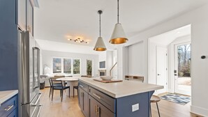 Una cucina moderna con una grande isola, elettrodomestici in acciaio inossidabile e illuminazione a sospensione.