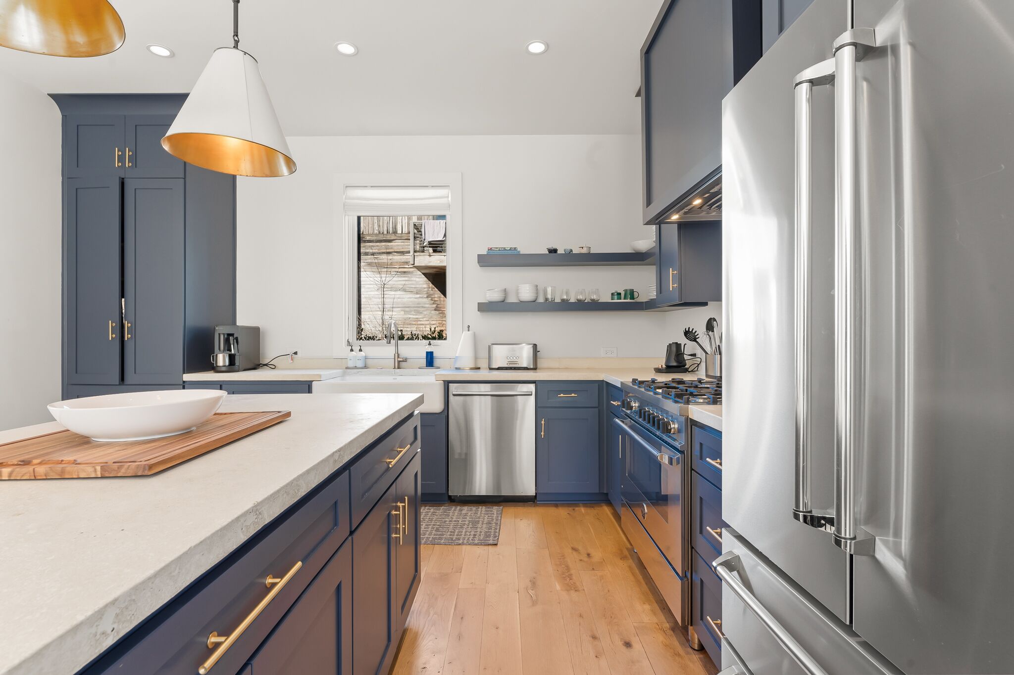 Une cuisine moderne avec des meubles bleu foncé, des appareils en acier inoxydable et un grand îlot central doté d’un évier.