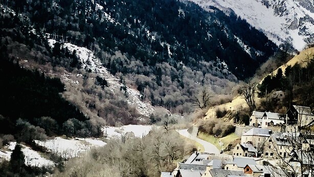 A rural village with stone buildings, a church, and a mountain backdrop.