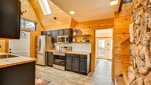 A kitchen with wooden walls, a stone wall, and a view of the outside.