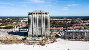 A high-rise hotel with a pool and beach view, surrounded by other buildings and a clear sky. - Oceanfront ex large balcony, Amazing panoramic views of Gulf from 16th floor (Panama City Beach)