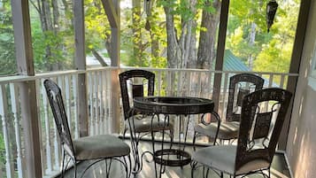 Relax in a serene outdoor space with a round table and four chairs, surrounded by a forest view through large windows.
