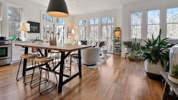 A modern kitchen with a wooden island, bar stools, and a pendant light.