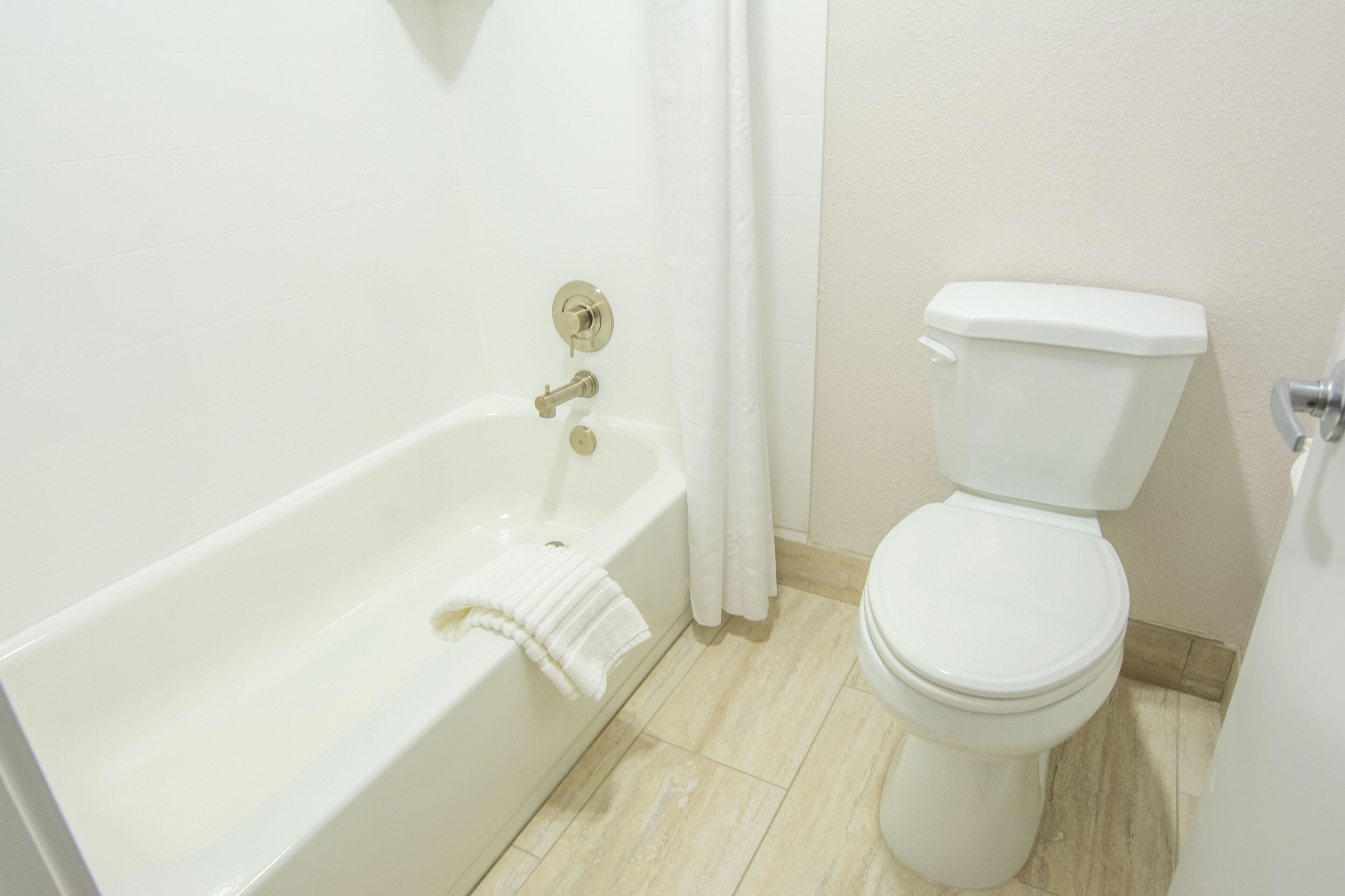 A bathroom with a white bathtub, a toilet, and a shower curtain.