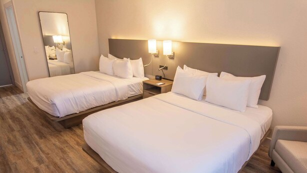 A hotel room with two single beds, a nightstand with a lamp, a mirror, and a chair. - Comfort Inn Battle Mountain - Midway Between Elko and Winnemucca (Battle Mountain)