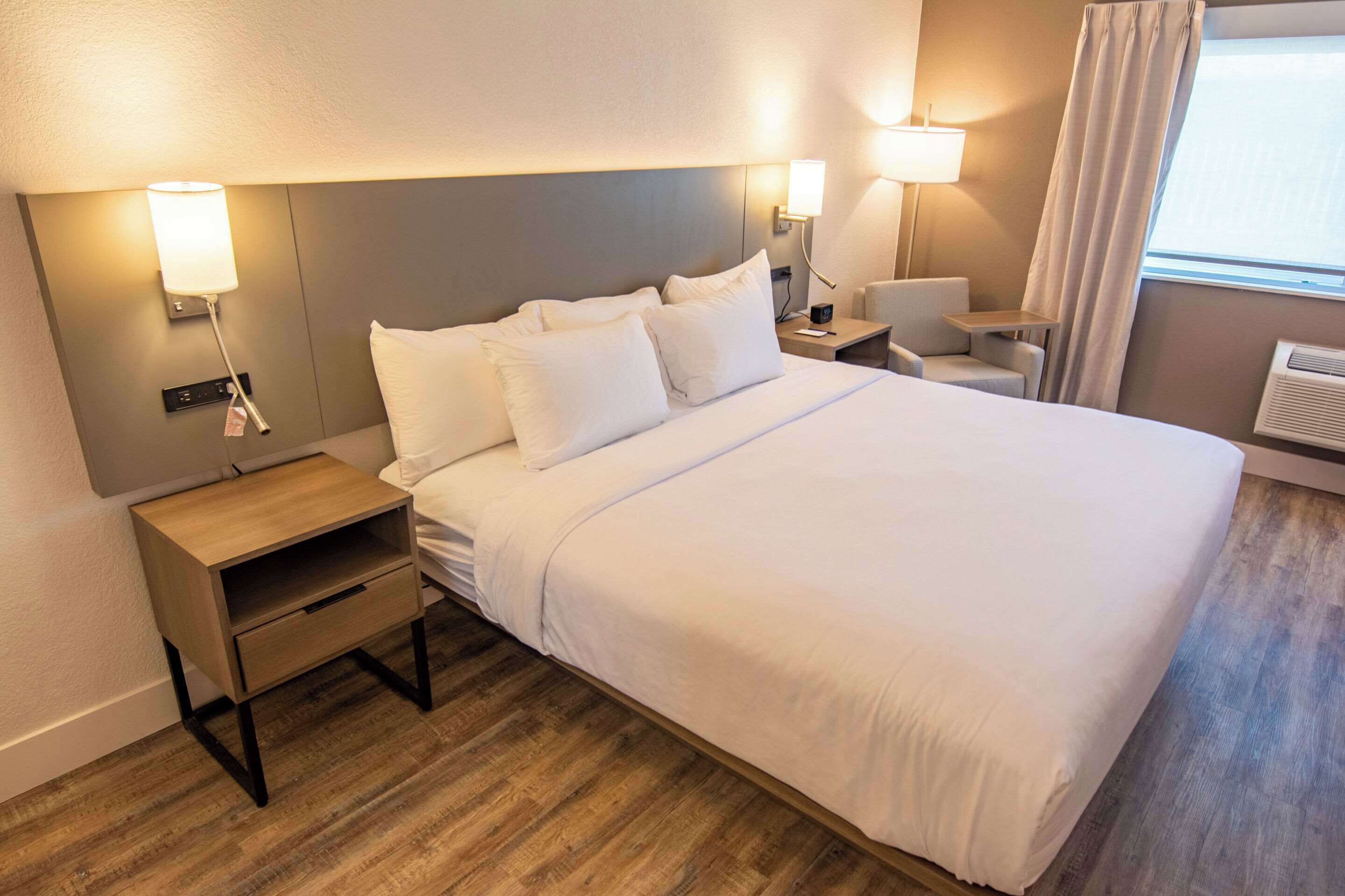 A hotel room with a large bed, bedside tables, a desk, and a chair.