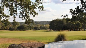 Campo de golf con un cuerpo de agua y árboles.