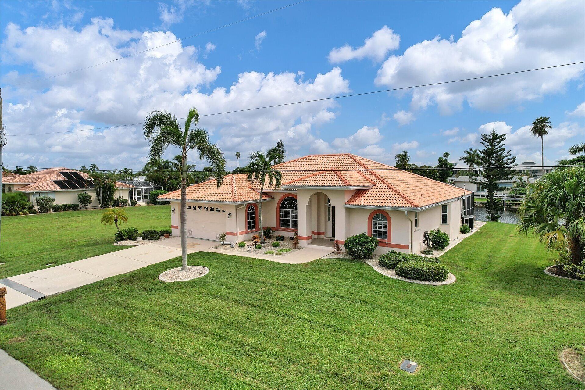 Ein eingeschossiges Haus mit rotem Ziegeldach, einem Hauseingang mit überdachter Veranda und einem gepflegten Rasen.