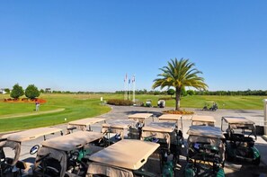 A golf course with multiple golf carts parked in a line, a palm tree, and flags in the background. - New Listing! Providence Resort, 9mi to Disney & 18mi to Universal - FS104972 (Davenport)