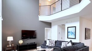 A modern living room with a grey sofa, a flat-screen TV, and a small table with a lamp. - New Listing! Providence Resort, 9mi to Disney & 18mi to Universal - FS104972 (Davenport)