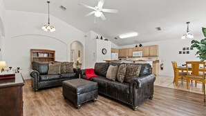 A spacious living room with leather sofas, a wooden coffee table, and a dining area with wooden chairs.